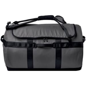 A grey duffle bag with black straps and handles, featuring a logo on the side.