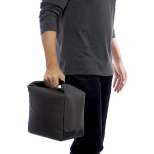 A black cooler bag is being held by a person, featuring a sturdy handle and a simple, sleek design.