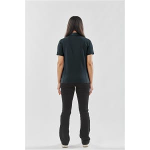 A woman wearing a black polo shirt stands with her back to the viewer, paired with black pants. The shirt has a logo.