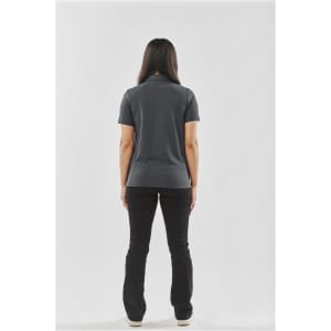 A woman stands with her back to the camera, wearing a dark grey women's polo shirt paired with black pants.