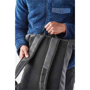 A person holds a black Sargasso Backpack with padded straps, wearing a blue fleece jacket.