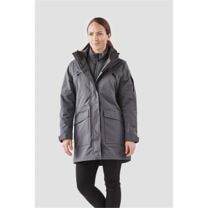 A woman in a grey 5-in-1 system jacket featuring multiple pockets and a hood, standing against a light background.