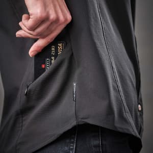 A close-up of a black women's button-up shirt with a zippered pocket. The shirt features a logo on the side.