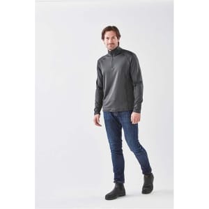 A man wearing a charcoal grey 1/4 zip long sleeve shirt paired with jeans and boots, standing against a neutral background.
