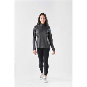 A long sleeve, quarter-zip jumper in dark grey, paired with black leggings and white sneakers, featuring a logo.