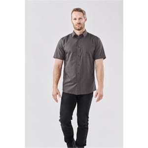 A short-sleeved button-up shirt in grey with a subtle pattern, worn by a male model with a logo present.