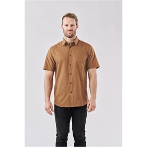 A short-sleeved, button-up shirt in a brown colour with a dotted pattern, featuring a logo on the chest.