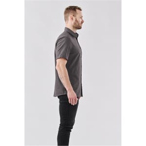 A grey short-sleeved button-up shirt worn by a man, featuring a subtle pattern. The shirt has a logo.