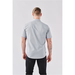 A light blue short-sleeved button-up shirt viewed from the back, featuring visible stitching and a logo label.