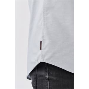A light grey button-up shirt with a side tag detail, shown from a close-up angle.