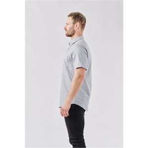 A grey men's short-sleeve button-up shirt displayed on a model from the side. The shirt features a pocket and has a branding logo.