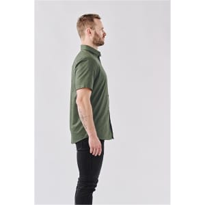 A side view of a man wearing an olive green short-sleeve button-up shirt. The shirt features a logo.