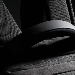 A black backpack featuring padded straps and textured fabric, with a small logo visible.
