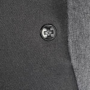A close-up of a black button on a grey fabric, featuring a simple embossed design.