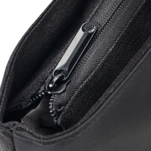 A close-up of a black tote bag's zippered pocket, showcasing its fabric texture and zipper details.