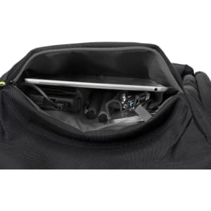 An open black backpack revealing a laptop, cables, and other accessories inside. It features a logo.