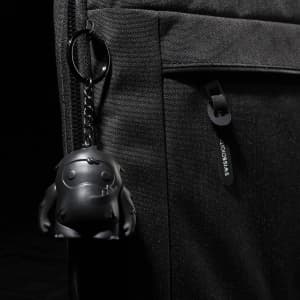 A black laptop sleeve features a textured surface and a keychain with a small black character.