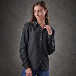 A woman models a long-sleeve, button-up shirt in dark grey, featuring a front pocket and a subtle logo.