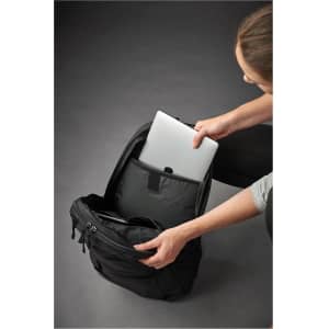 A person placing a silver laptop into a black laptop bag, featuring a sleek design and multiple compartments.