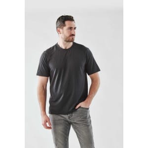 A man wearing a black short sleeve performance T-shirt, styled with casual jeans, against a light grey background.