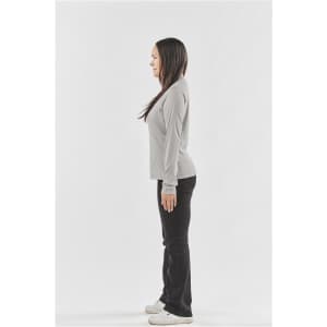 A woman stands in profile wearing a long-sleeve light grey t-shirt and black pants, with a logo visible on the shirt.