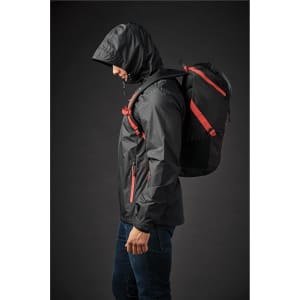 A black Whistler Backpack with red straps is worn by a person in a jacket, shown against a dark background.
