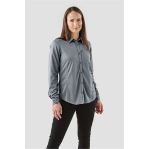 A woman wearing a grey long sleeve button-up shirt with a chest pocket and a logo.