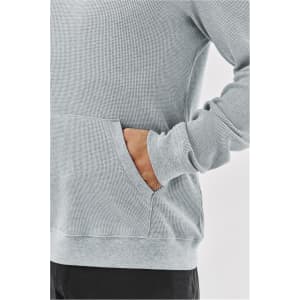 A grey pullover hoodie featuring a textured fabric and a front pocket. It has a logo on the design.