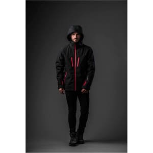 A man stands wearing a black jacket with red accents and a hood, featuring a branding logo.