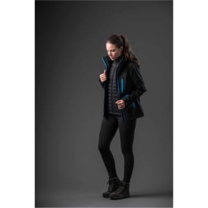 A woman wearing a black jacket with blue accents, paired with sleek black leggings and hiking boots.