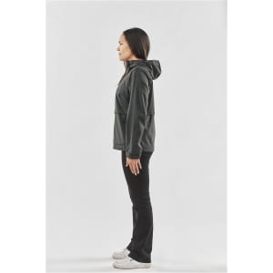 A woman wearing a black rain jacket with a hood, standing in profile against a plain background.