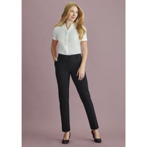 A woman wearing black bandless elastic waist pants paired with a white shirt and heels, standing against a purple background.