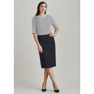 A woman stands wearing a navy lined skirt with a relaxed fit, paired with a striped top and heels.
