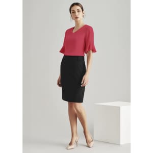 A woman wearing a red top and a black, knee-length pleat skirt, standing on a neutral background.
