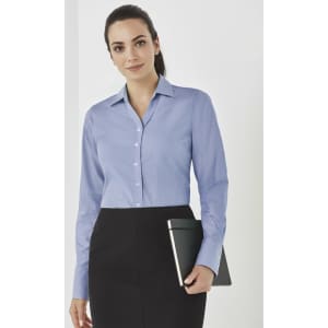 A woman in a light blue long sleeve button-up shirt, holding a tablet, paired with a black skirt.