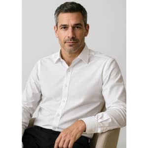 A stylish white button-up shirt on a seated man, featuring a classic collar and an understated design.