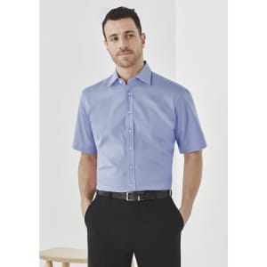 A short sleeve button-up shirt in light blue, featuring a collar and a logo, paired with black trousers.
