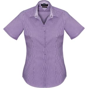 A women's short sleeve button-up shirt in a purple check pattern, featuring a collar and a logo.