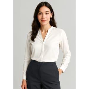 A white long sleeve blouse with a v-neckline and button-up design, paired with dark grey trousers.