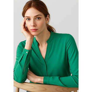 A green long sleeve blouse with a V-neck design, featuring button details on the sleeves. The model poses thoughtfully.