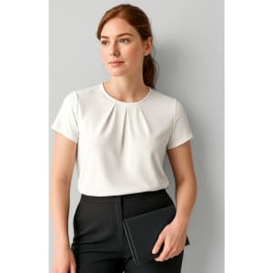 A woman in a white short sleeve top poses against a light grey background, holding a black clutch.