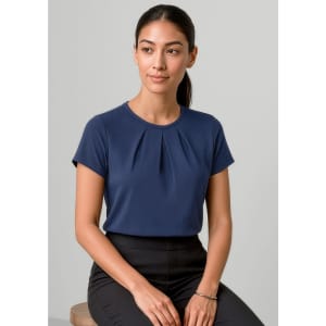 A navy short sleeve top with pleats, featuring a logo, displayed on a model.
