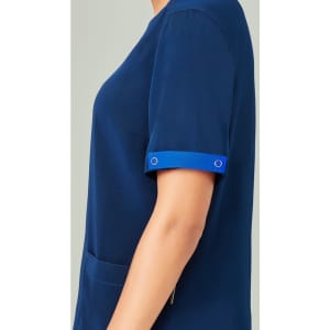 Unisex scrub top in navy with blue accents on the rolled sleeves, featuring a pocket on the side.