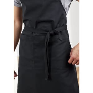 A black apron featuring a waist tie and front pockets, designed for practical workwear use.