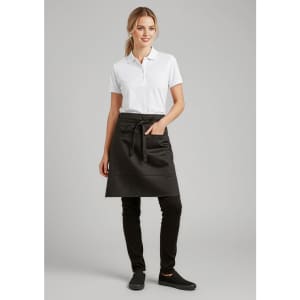 A woman wearing a black short waisted apron over a white polo shirt, paired with black pants and shoes.