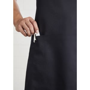 A black bib apron with a hand inserting a clip into a pocket, featuring a logo.