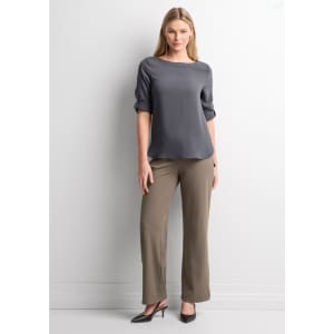 A woman stands wearing grey soft stretch pants and a grey top, complemented by black high heels against a neutral background.