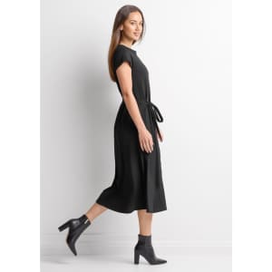 A black midi dress with short sleeves and a tied waist, featuring a model walking in profile.