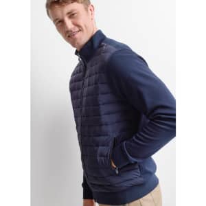 A men's tailor jacket in navy blue, featuring a quilted front and side pockets, worn by a smiling model.