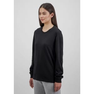 A women's long sleeve tee in black, featuring a round neck and long sleeves, displayed on a model.